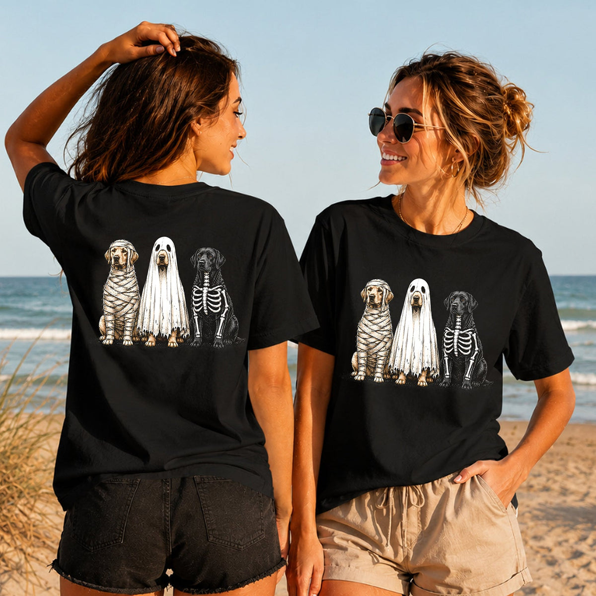 Halloween Dog Trio - Women's T-Shirt in black, showing alternative back and front print placements on the beach