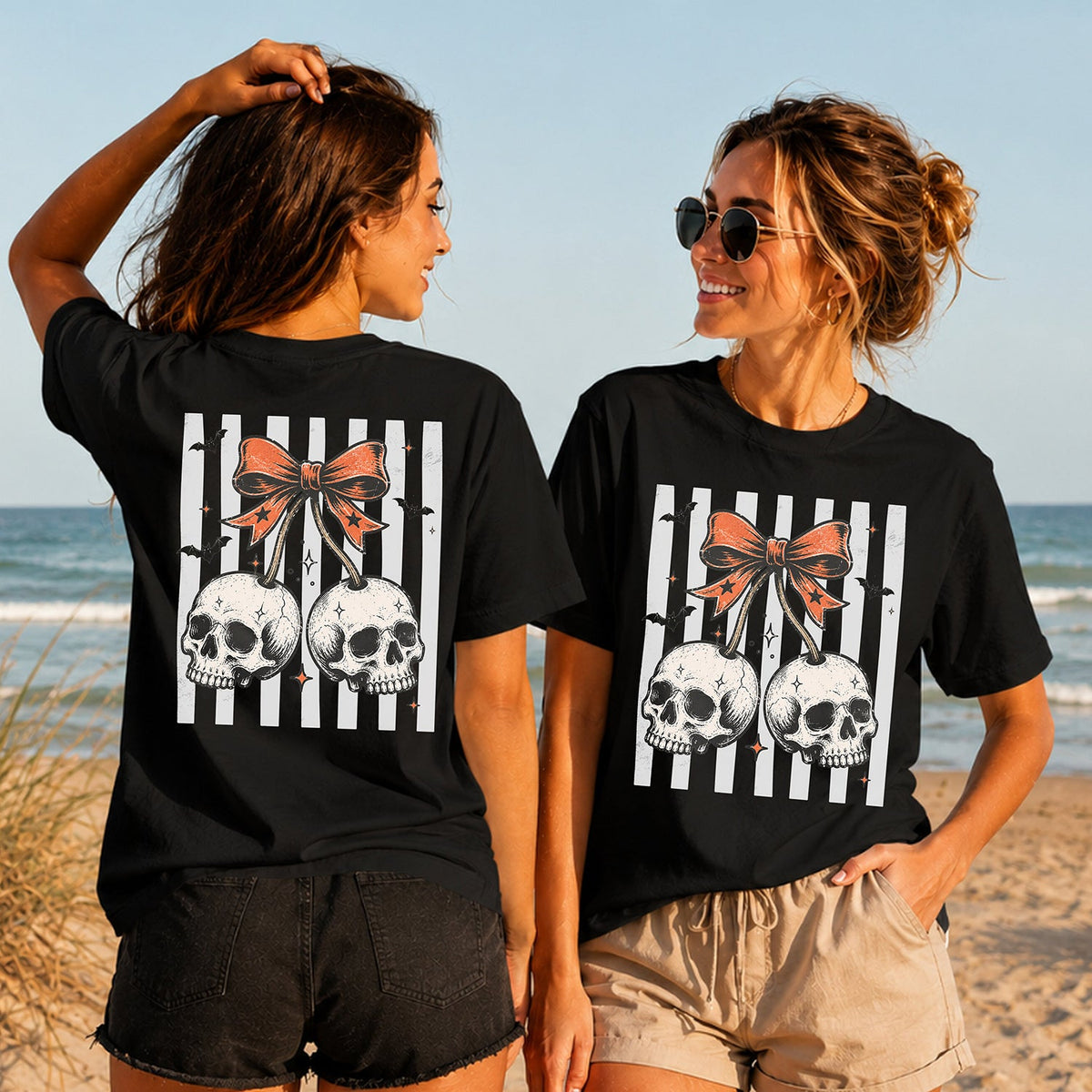 Halloween Skull Cherries - Women's T-Shirt in black, showing alternative back and front print placements on the beach