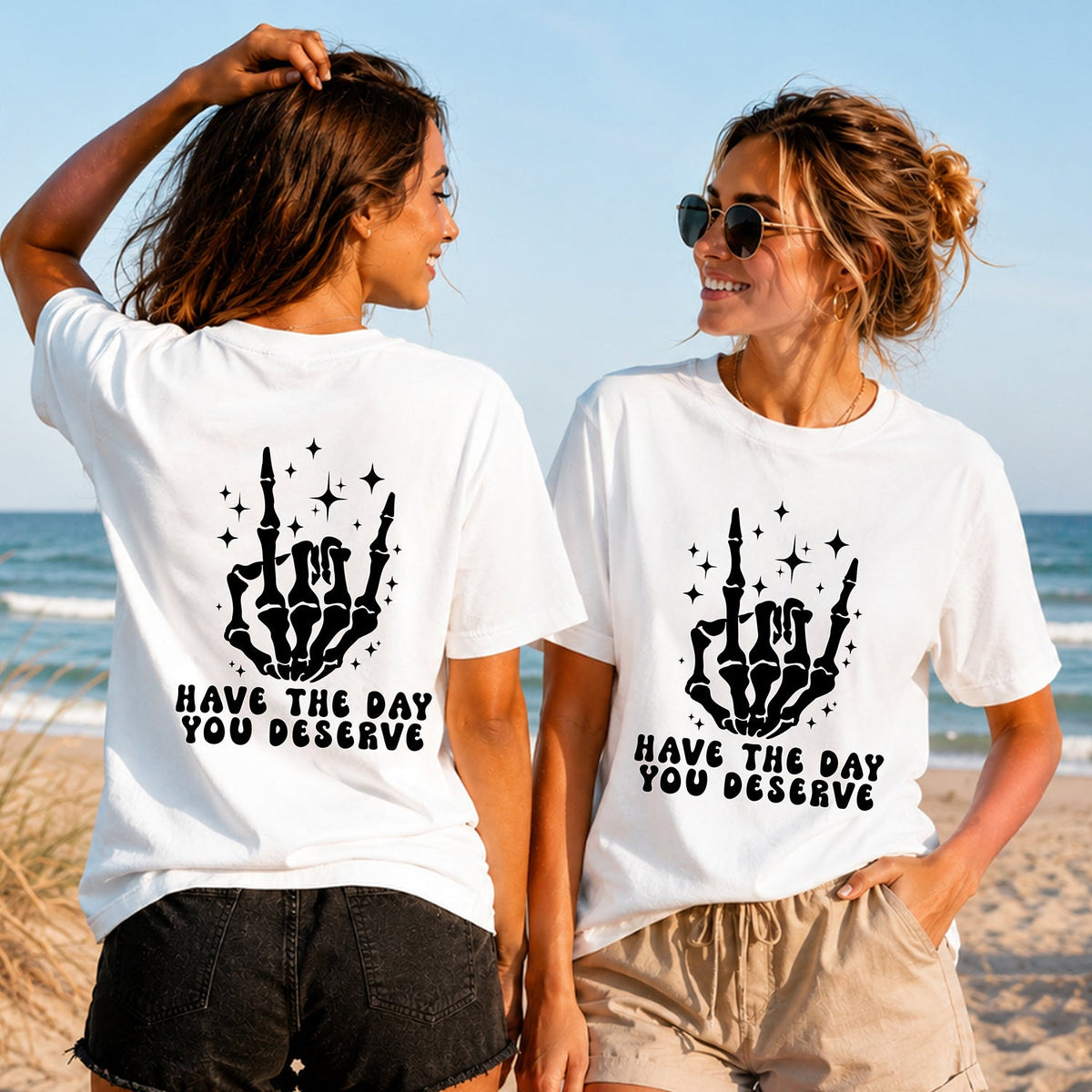 Have the Day You Deserve - Skeleton Hand - Women's T-Shirt in white, showing alternative back and front print placements on the beach