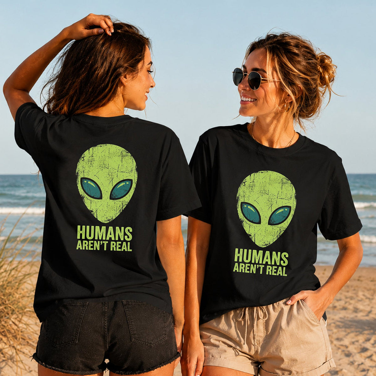 Humans Aren't Real - Women's T-Shirt in black, showing alternative back and front print placements on the beach