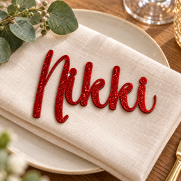 Nikki in Creativenotes font, Bright Red Glitter Acrylic personalised guest name on an ivory napkin.