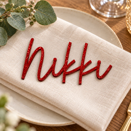 Nikki in Framhouse font, Bright Red Glitter Acrylic personalised guest name on an ivory napkin.