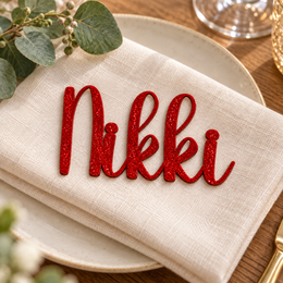 Nikki in Ladybug font, Bright Red Glitter Acrylic personalised guest name on an ivory napkin.