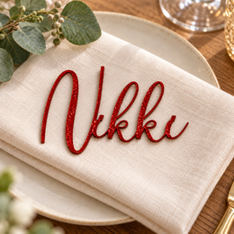 Nikki in Potography font, Bright Red Glitter Acrylic personalised guest name on an ivory napkin.